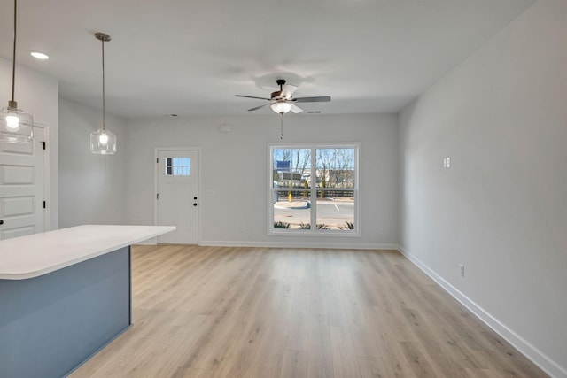 interior space with light wood-style flooring, a ceiling fan, and baseboards