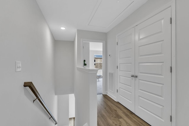 hallway featuring an upstairs landing, visible vents, attic access, and wood finished floors