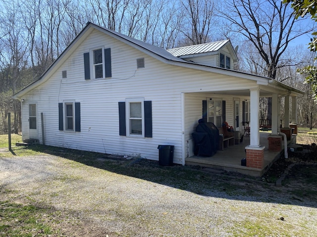 view of side of property featuring metal roof and covered porch