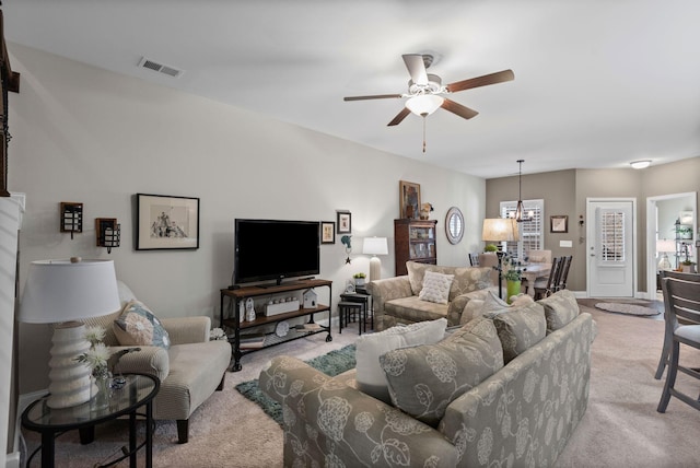 living room featuring visible vents, light carpet, baseboards, and ceiling fan with notable chandelier