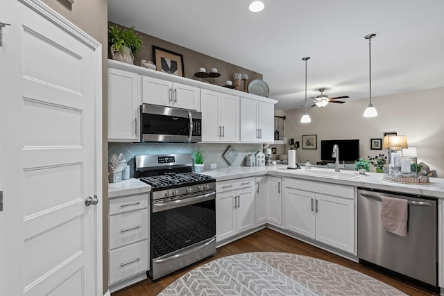 kitchen with backsplash, stainless steel appliances, white cabinetry, a ceiling fan, and a sink