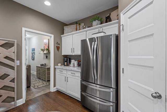 kitchen featuring dark wood-style flooring, freestanding refrigerator, light countertops, white cabinets, and tasteful backsplash