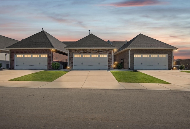 view of front of home featuring brick siding, roof with shingles, and driveway