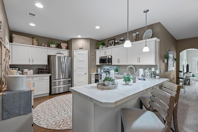 kitchen with a breakfast bar area, appliances with stainless steel finishes, a peninsula, arched walkways, and white cabinets