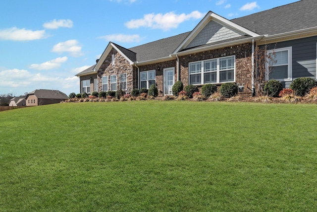 craftsman-style house featuring roof with shingles and a front lawn