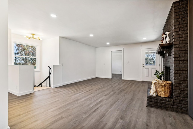 unfurnished living room featuring recessed lighting, a fireplace, baseboards, and wood finished floors