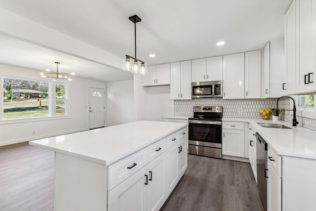 kitchen with a wealth of natural light, a sink, backsplash, wood finished floors, and stainless steel appliances