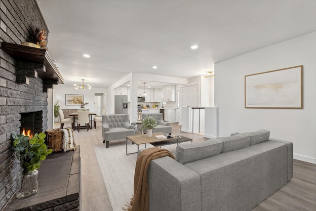 living area featuring a notable chandelier, wood finished floors, recessed lighting, a fireplace, and baseboards