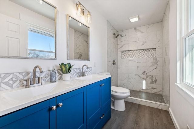 full bathroom with a sink, tiled shower, and wood finished floors