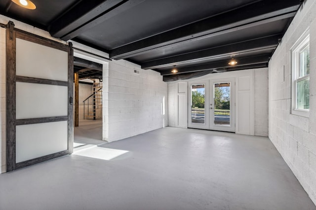 below grade area featuring a barn door, concrete block wall, stairs, and french doors