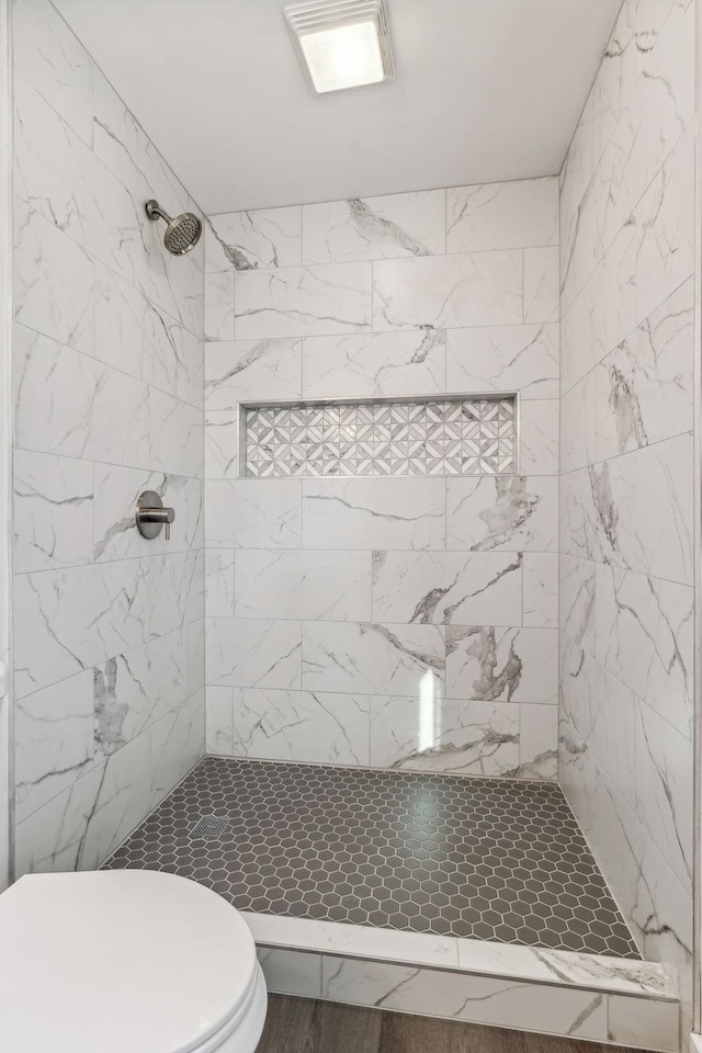 bathroom with tiled shower and toilet