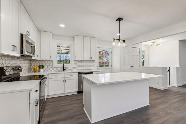 kitchen with dark wood-type flooring, a sink, white cabinetry, stainless steel appliances, and decorative backsplash