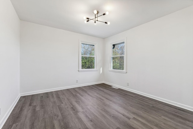 spare room with visible vents, baseboards, and dark wood-style flooring