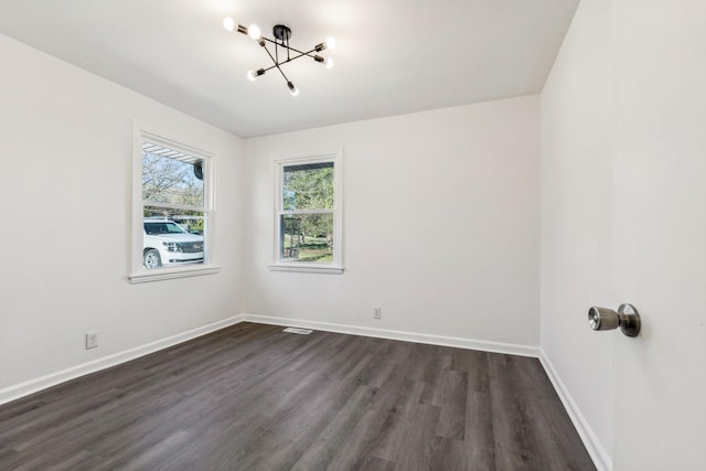 empty room with baseboards, an inviting chandelier, and dark wood-style flooring