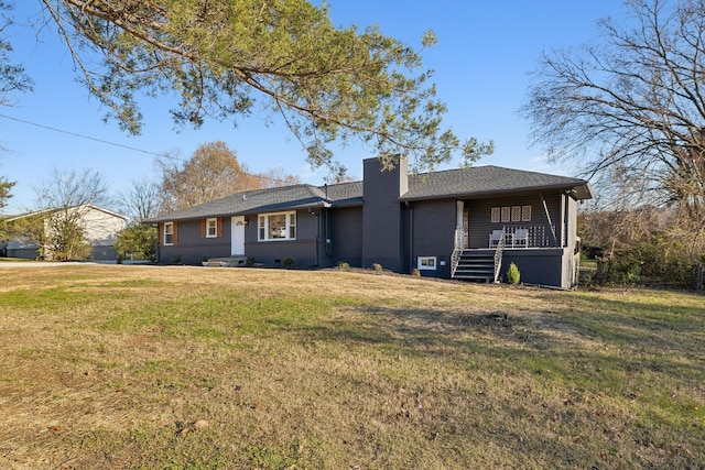 view of front of house featuring brick siding, covered porch, a chimney, and a front yard