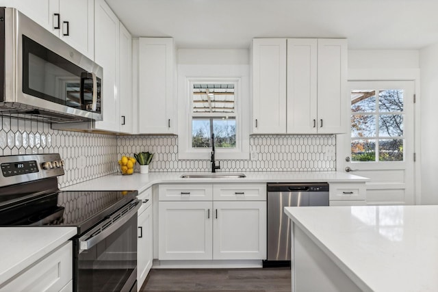 kitchen with tasteful backsplash, light countertops, stainless steel appliances, white cabinetry, and a sink