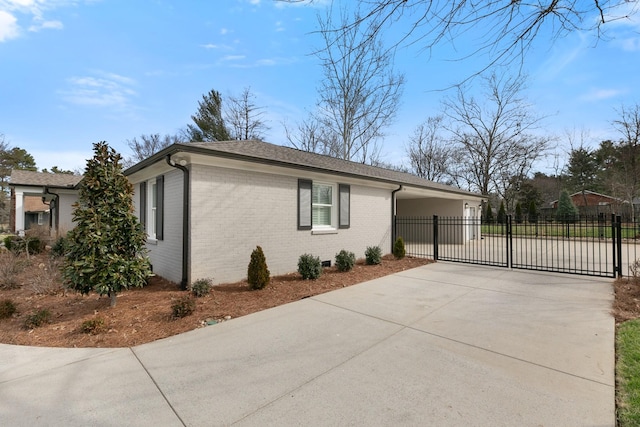 view of home's exterior featuring fence, brick siding, driveway, and a gate