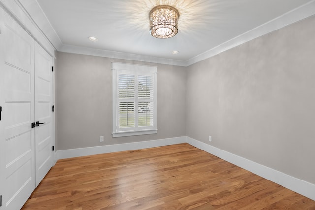 unfurnished bedroom with a notable chandelier, baseboards, crown molding, and light wood-style floors