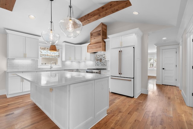 kitchen with high end refrigerator, a center island, white cabinetry, light countertops, and vaulted ceiling with beams