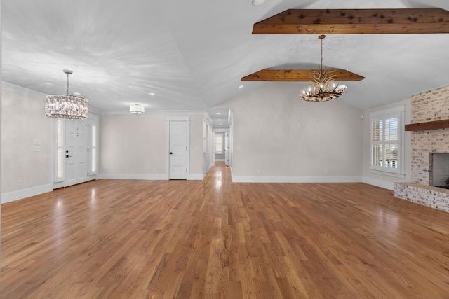 unfurnished living room with lofted ceiling with beams, a brick fireplace, an inviting chandelier, and light wood-style flooring