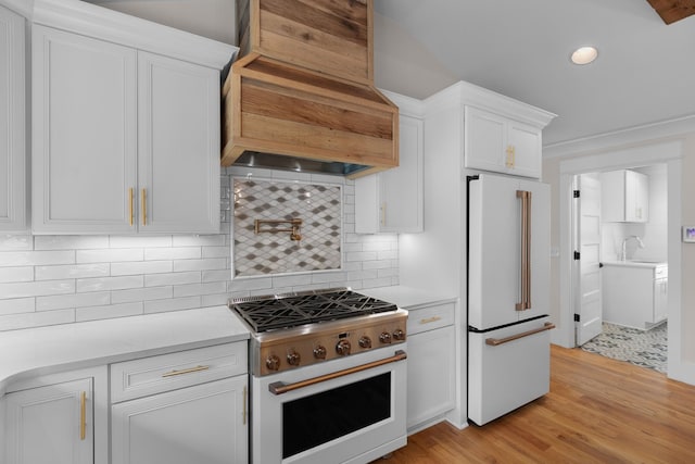 kitchen featuring custom range hood, range with gas stovetop, light countertops, and freestanding refrigerator