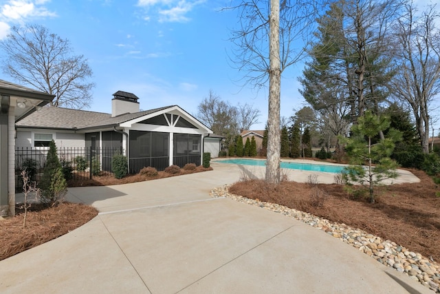 view of pool featuring a patio area, a fenced in pool, fence, and a sunroom