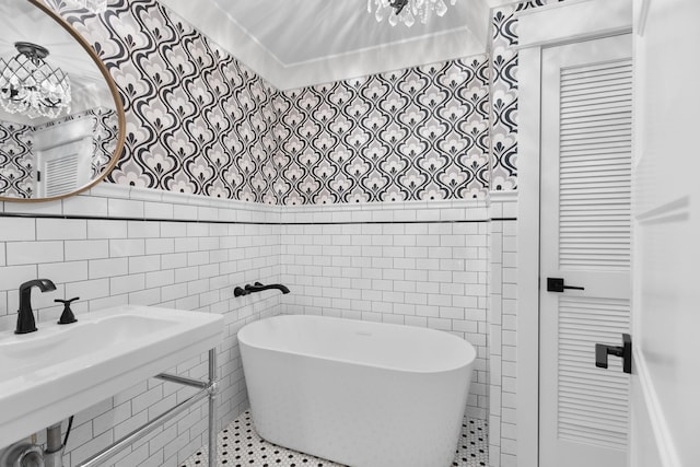 bathroom with a wainscoted wall, a freestanding bath, tile walls, and a sink