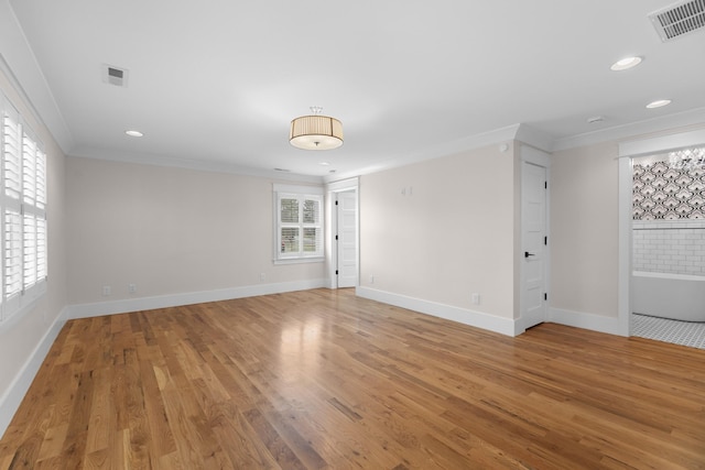 spare room featuring visible vents, plenty of natural light, ornamental molding, and light wood-style flooring