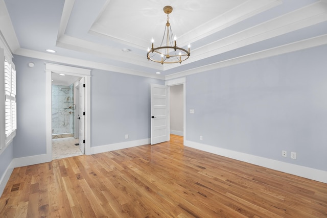 unfurnished bedroom with light wood finished floors, visible vents, baseboards, a chandelier, and a tray ceiling