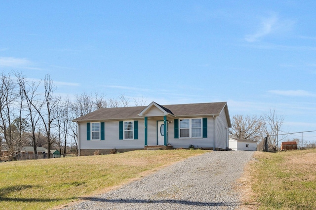 ranch-style home featuring an outbuilding, gravel driveway, and a front yard