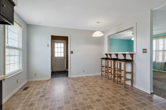 interior space featuring visible vents, baseboards, a textured ceiling, and a healthy amount of sunlight