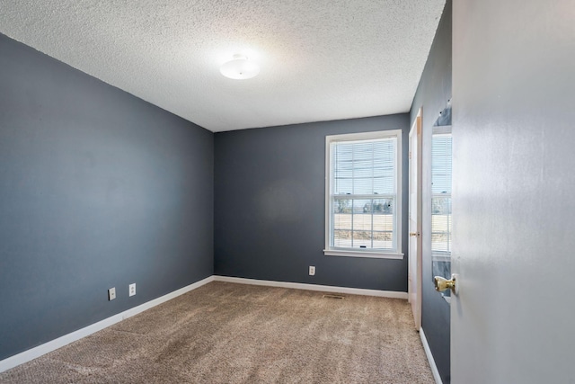 unfurnished room featuring carpet, baseboards, and a textured ceiling