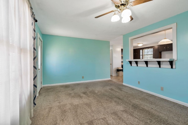 unfurnished living room with ceiling fan, baseboards, and carpet floors