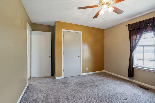 unfurnished bedroom with visible vents, multiple windows, baseboards, and carpet floors