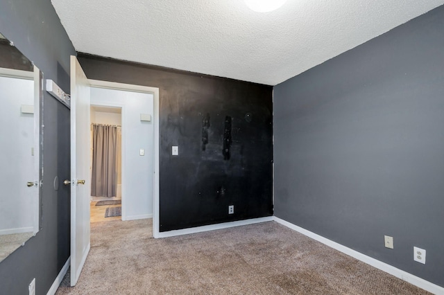 carpeted spare room with baseboards and a textured ceiling