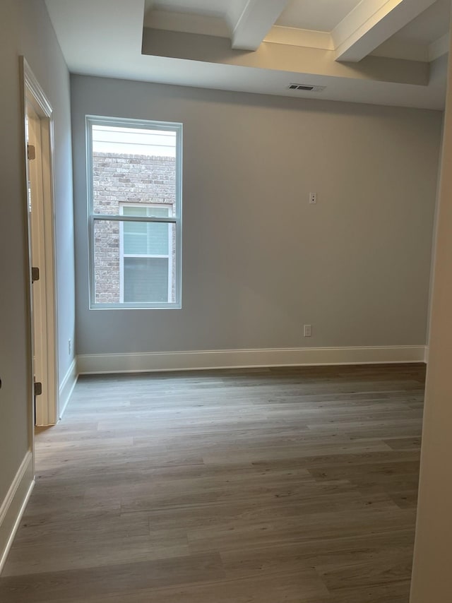 unfurnished room with beamed ceiling, wood finished floors, visible vents, and baseboards