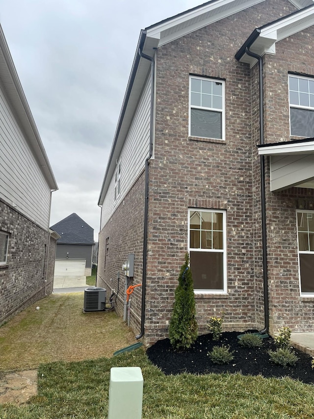 view of side of home with a yard, central AC unit, and brick siding