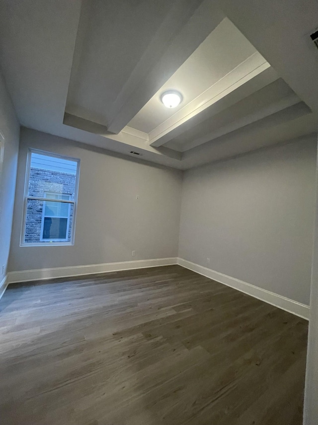 spare room with dark wood finished floors, beamed ceiling, and baseboards