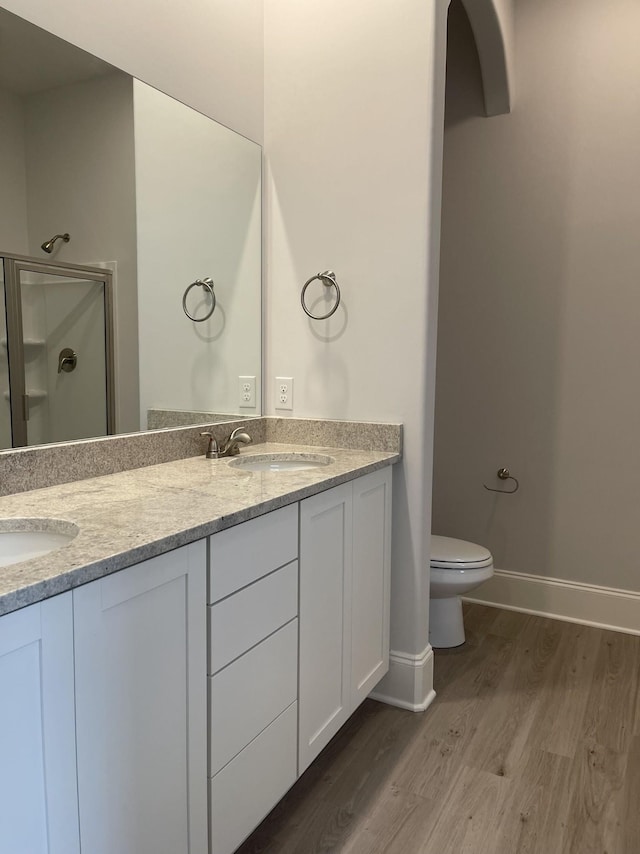 full bathroom with a sink, double vanity, wood finished floors, and a shower stall