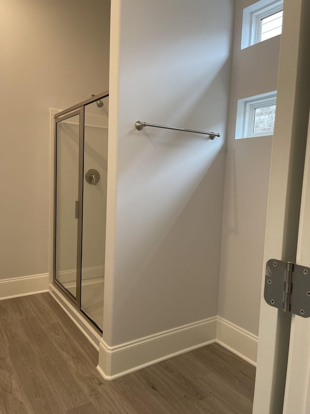 bathroom with baseboards, wood finished floors, and a stall shower