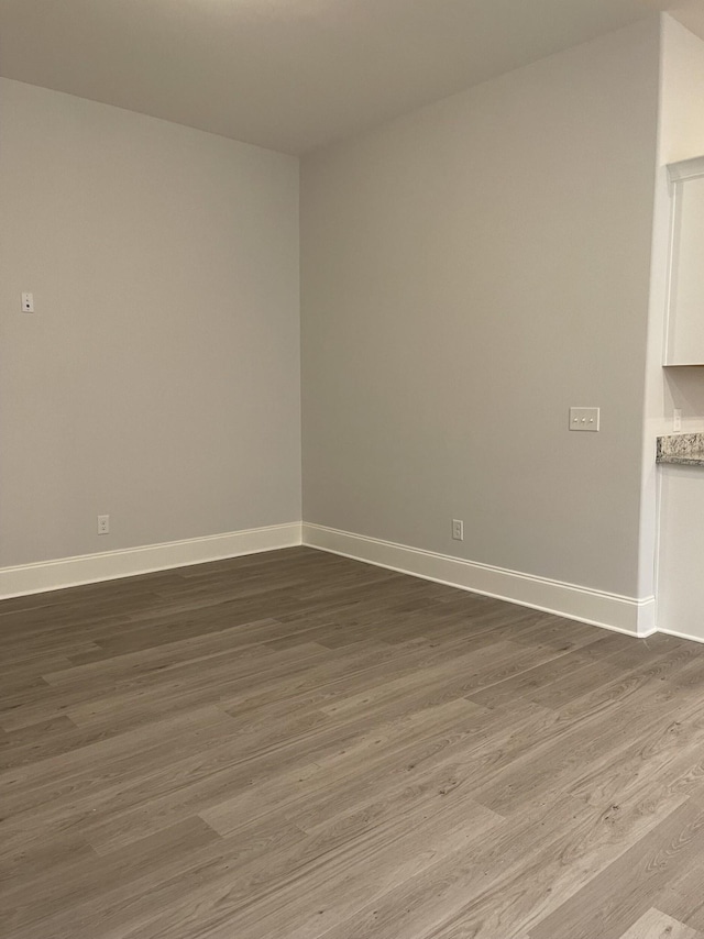 unfurnished room featuring baseboards and dark wood finished floors