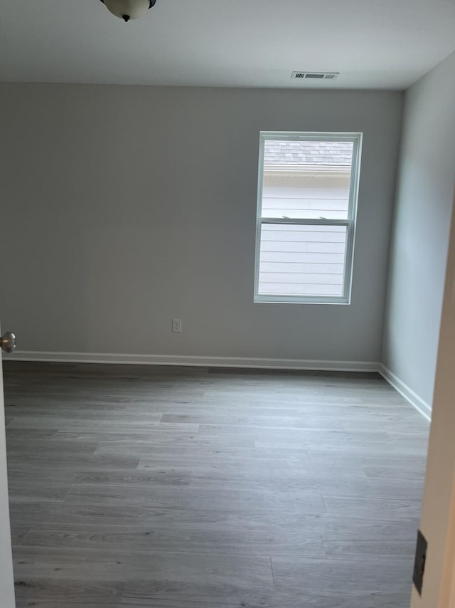 spare room featuring wood finished floors, baseboards, and visible vents