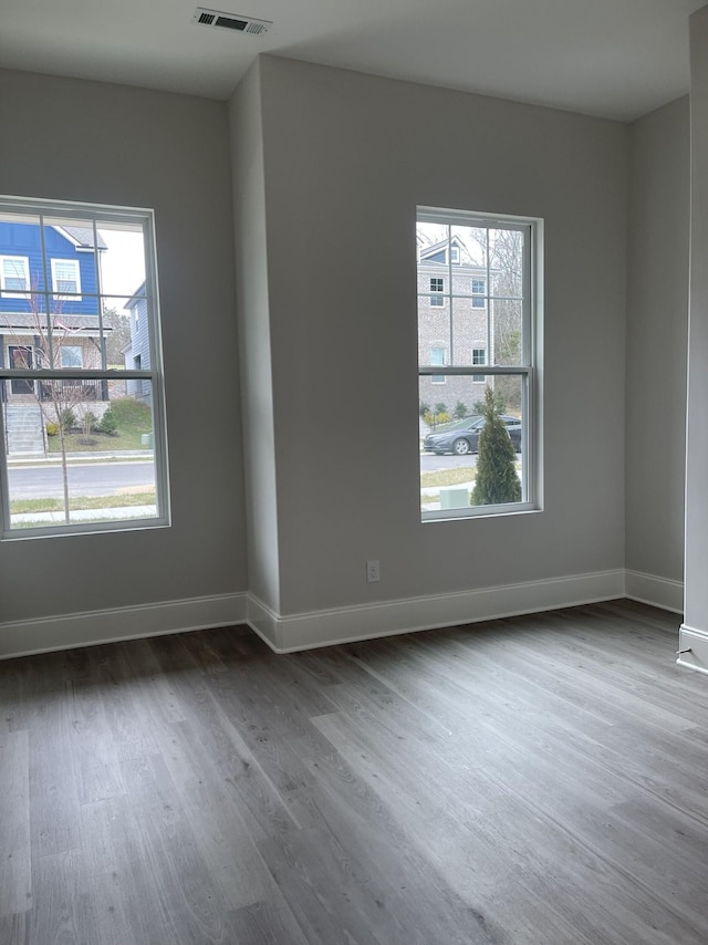 unfurnished room featuring visible vents, baseboards, and wood finished floors