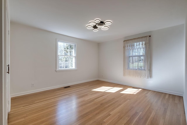 spare room with visible vents, baseboards, and light wood-style floors