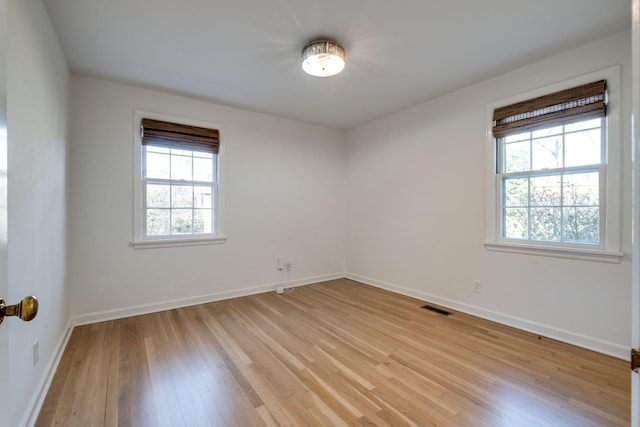 empty room featuring visible vents, light wood-style flooring, and baseboards