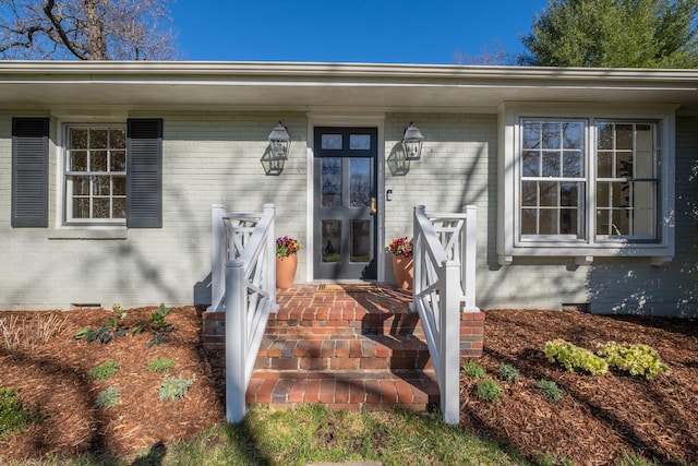 doorway to property with crawl space and brick siding