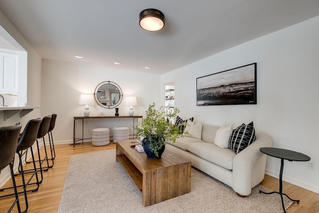 living room featuring recessed lighting, baseboards, and light wood finished floors