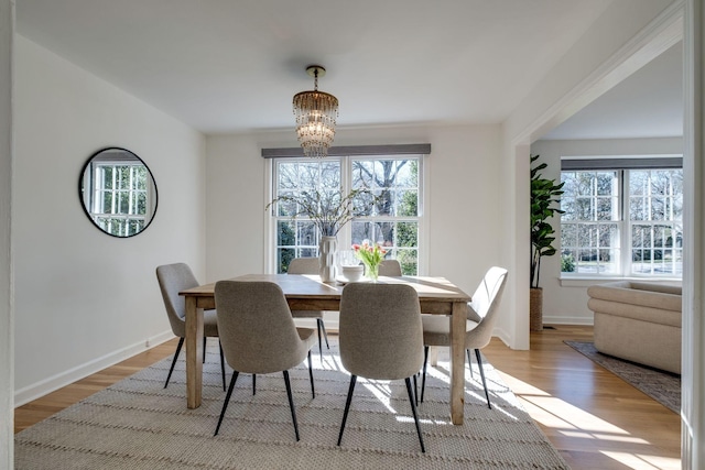 dining space featuring baseboards, an inviting chandelier, and light wood-style flooring