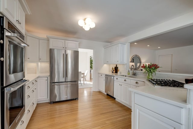 kitchen featuring a sink, light wood-style floors, white cabinetry, and stainless steel appliances