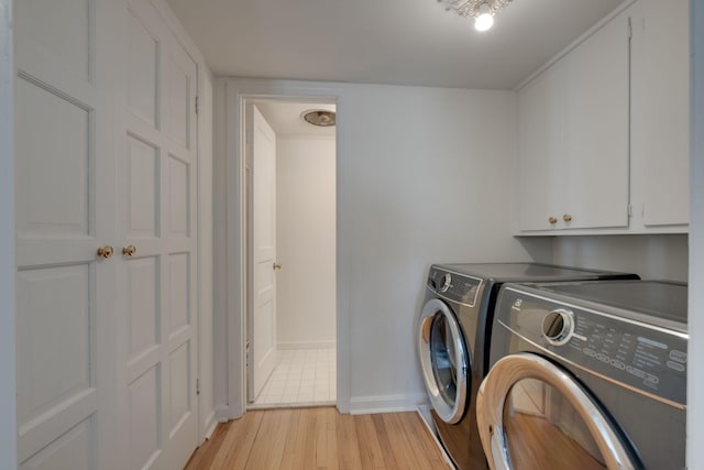 washroom with light wood-style flooring, cabinet space, baseboards, and washing machine and dryer